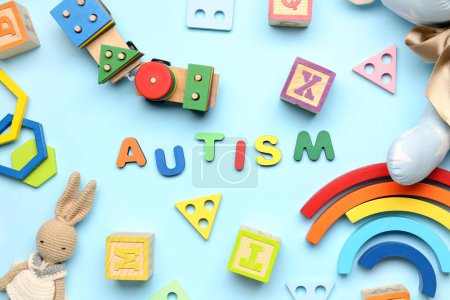 Téléchargez les photos : Word AUTISM avec des jouets pour bébés sur fond bleu. Journée mondiale de sensibilisation à l'autisme - en image libre de droit