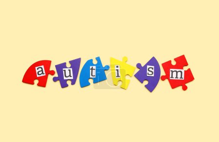 Photo for Word AUTISM with puzzle pieces on beige background - Royalty Free Image