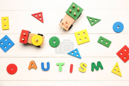 Photo for Word AUTISM with baby toys on white wooden background - Royalty Free Image