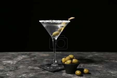 Glas leckerer Martini mit Oliven auf dunklem Hintergrund