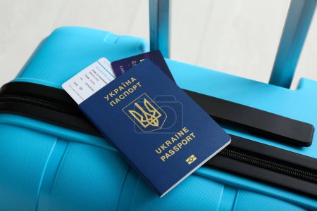 Koffer mit ukrainischem Pass auf weißem Holzgrund, Nahaufnahme