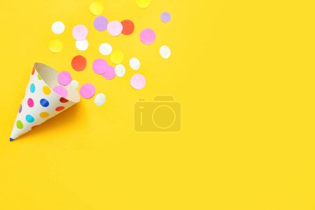 Foto de Composición con sombrero de fiesta y confeti sobre fondo amarillo - Imagen libre de derechos