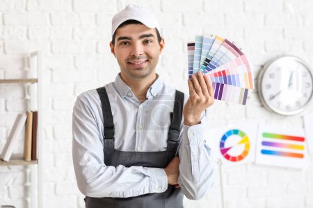 Foto de Pintor masculino con paletas de colores cerca de la pared de ladrillo blanco - Imagen libre de derechos