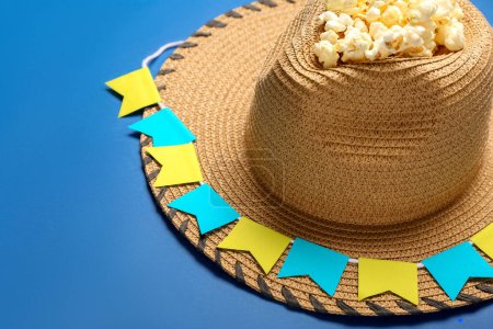 Foto de Sombrero de paja con palomitas de maíz y banderas sobre fondo azul, primer plano. Festa Junina (Festival de Junio) celebración - Imagen libre de derechos