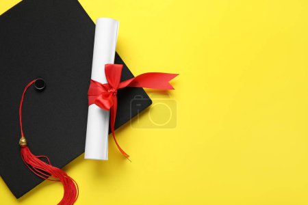 Photo for Diploma with red ribbon and graduation hat on yellow background - Royalty Free Image