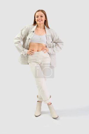 Pretty young woman in stylish clothes on light background Poster 649738012
