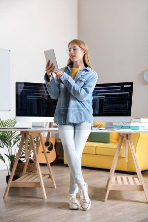Téléchargez les photos : Programmeur femelle travaillant avec un ordinateur tablette au bureau - en image libre de droit