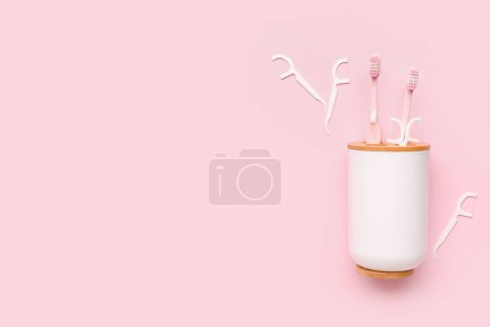 Foto de Soporte de cepillo de dientes volcado y mondadientes de hilo dental sobre fondo rosa - Imagen libre de derechos