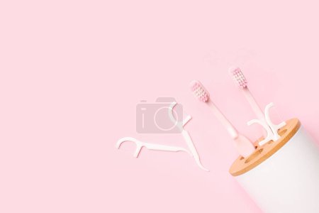 Foto de Soporte de cepillo de dientes volcado y mondadientes de hilo dental sobre fondo rosa - Imagen libre de derechos