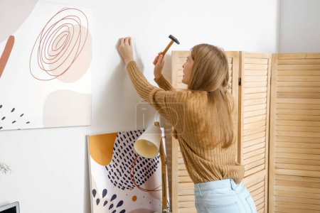 Téléchargez les photos : Jeune femme clouant sur un mur léger à la maison - en image libre de droit