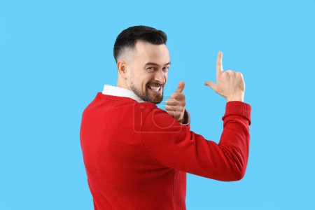 Photo for Handsome man showing loser gesture on blue background - Royalty Free Image
