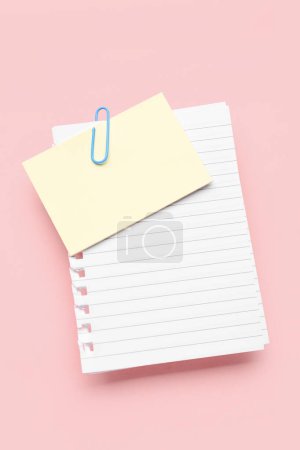 Feuilles de papier avec clip sur fond rose