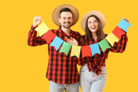 Photo for Young couple with flags on yellow background. Festa Junina (June Festival) celebration - Royalty Free Image