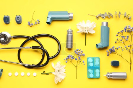 Téléchargez les photos : Inhalateurs d'asthme avec stéthoscope, pilules et fleurs sur fond jaune - en image libre de droit