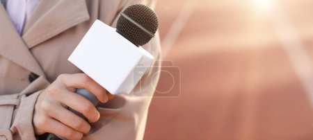 Journaliste féminine avec microphone au stade, gros plan