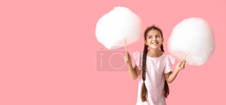 Linda niña con algodón de azúcar sobre fondo rosa con espacio para el texto