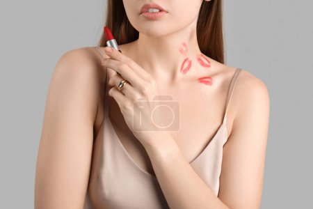 Foto de Mujer joven con marcas de lápiz labial y mordedura de amor en el cuello contra fondo gris, primer plano - Imagen libre de derechos