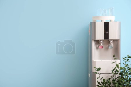 Photo for Modern water cooler and houseplant on blue background - Royalty Free Image