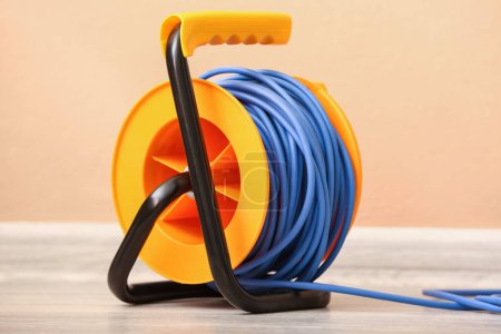 Foto de Carrete de cable eléctrico de extensión en el suelo cerca de la pared de color, primer plano - Imagen libre de derechos