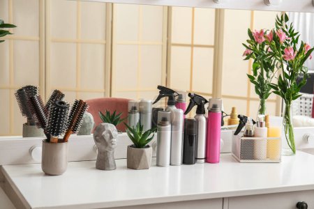 Verschiedene Sprays, Pinsel und Haarpflegeprodukte auf dem Tisch im Schönheitssalon