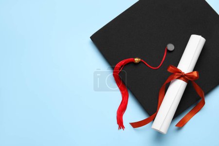 Photo for Diploma with red ribbon and graduation hat on blue background - Royalty Free Image