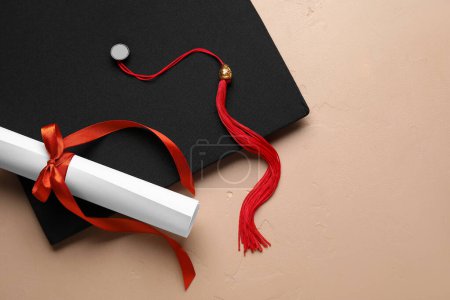 Photo for Diploma with red ribbon and graduation hat on beige table - Royalty Free Image