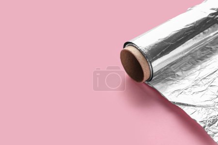 Aluminium foil roll on pink background