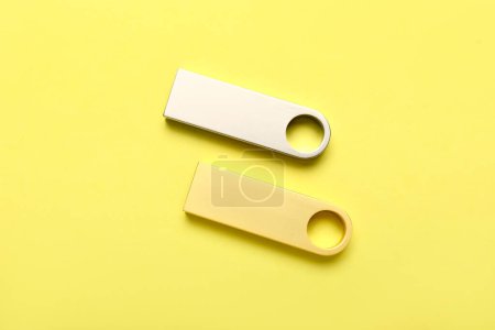Foto de Unidades flash USB metálicas y doradas sobre fondo amarillo - Imagen libre de derechos