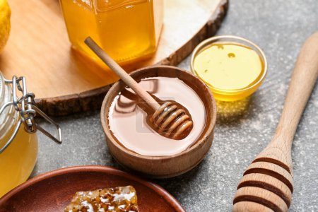 Foto de Cuenco de miel dulce con cazo sobre fondo gris - Imagen libre de derechos