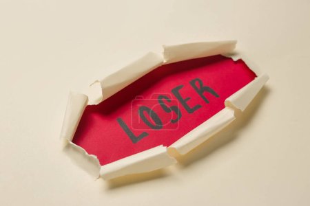 Word LOSER visible through hole in white paper, closeup