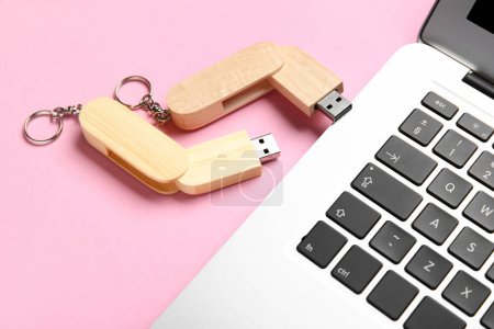 Foto de Unidades flash USB de madera y portátil moderno en fondo rosa - Imagen libre de derechos