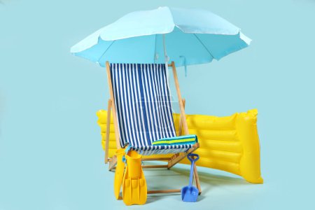 Liegestuhl, blauer Sonnenschirm und Strandaccessoires auf blauem Hintergrund