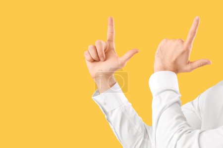 Photo for Young businessman showing loser gesture on yellow background - Royalty Free Image