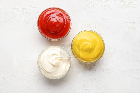 Téléchargez les photos : Bol de ketchup, mayonnaise et moutarde sur table de grunge blanche - en image libre de droit
