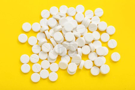 Photo for Heap of white pills on yellow background - Royalty Free Image