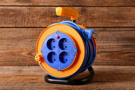 Photo for Extension electric cable reel on wooden background - Royalty Free Image