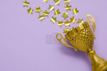 Gold cup with stars on lilac background, closeup