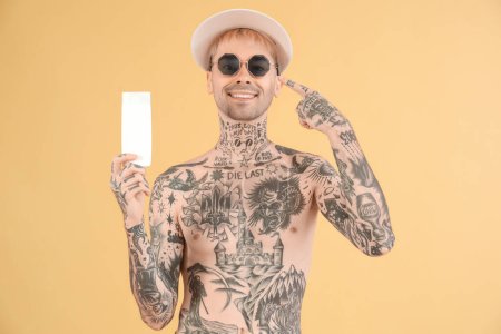 Hombre tatuado con crema protector solar sobre fondo beige