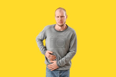 Téléchargez les photos : Jeune homme avec appendicite sur fond jaune - en image libre de droit
