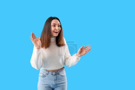 Beautiful happy young woman meeting someone on light blue background
