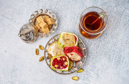 Téléchargez les photos : Assiette avec délicieux Délice turc et verre de thé sur fond clair - en image libre de droit