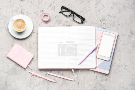 Foto de Composición con portátil, teléfono móvil, bolígrafos, vasos y taza de café sobre mesa gris - Imagen libre de derechos