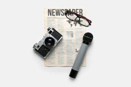 Téléchargez les photos : Journal avec microphone, appareil photo et lunettes sur fond blanc - en image libre de droit