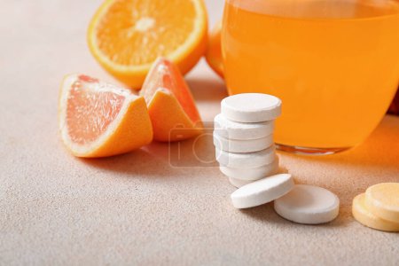 Comprimidos efervescentes de vitamina C y frutas en la mesa grunge gris