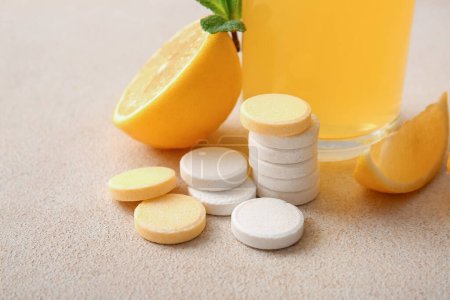 Tabletas efervescentes de vitamina C y limones en mesa grunge beige