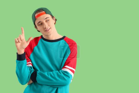Photo for Young man showing loser gesture on green background - Royalty Free Image
