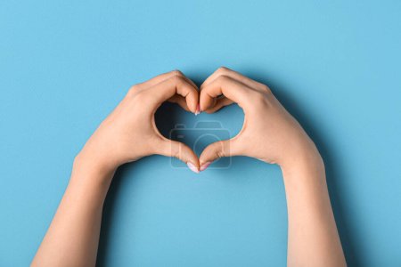 Téléchargez les photos : Femme faisant coeur avec ses mains sur fond bleu - en image libre de droit
