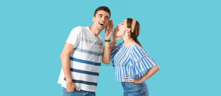 Photo for Young woman sharing gossip with her boyfriend on light blue background - Royalty Free Image