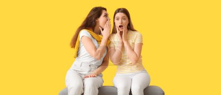 Photo for Young gossiping women on yellow background - Royalty Free Image