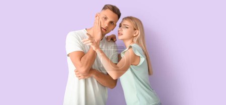 Photo for Gossiping young couple on lilac background - Royalty Free Image